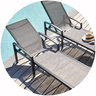 Tumbonas de textileno gris instaladas al borde de una piscina