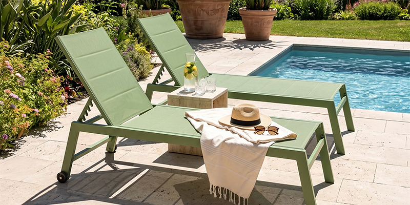 Tumbonas de aluminio con mesa auxiliar de madera junto a una piscina